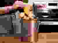 Woman putting banana peel into stainless steel countertop compost bin.