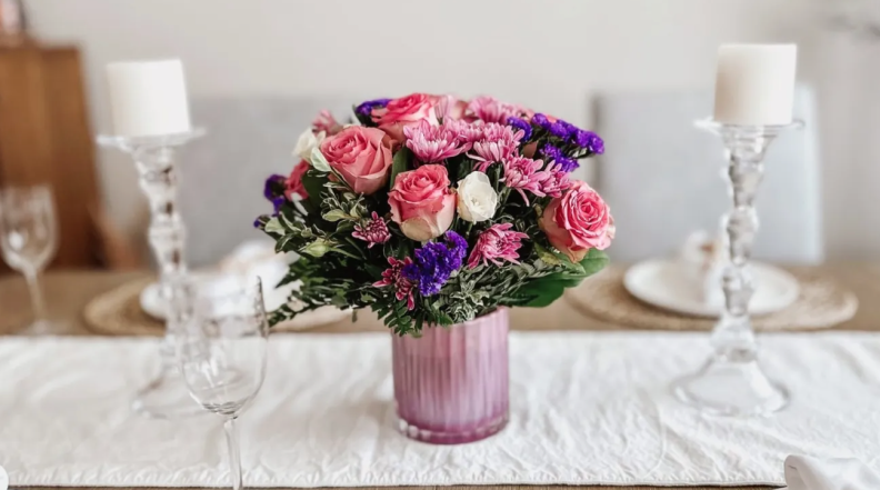 Colorful flower arrangement from Teleflora are arranged in a vase on top of a dining room table.